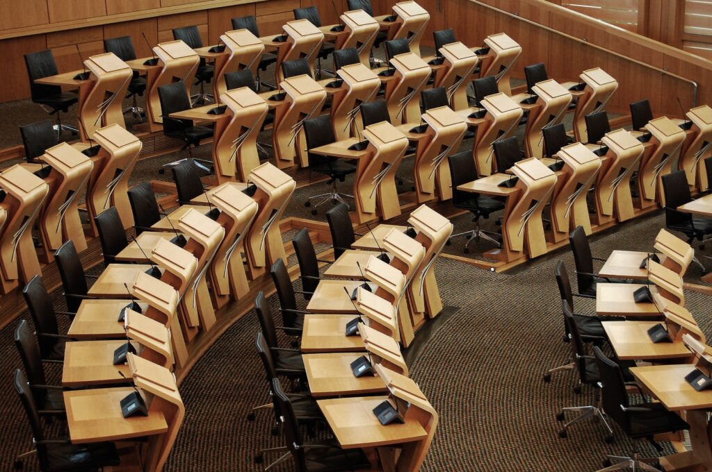 Mesas e cadeiras de um plenário vazias. Lugar onde discutem legislações, assuntos políticos e eleições.