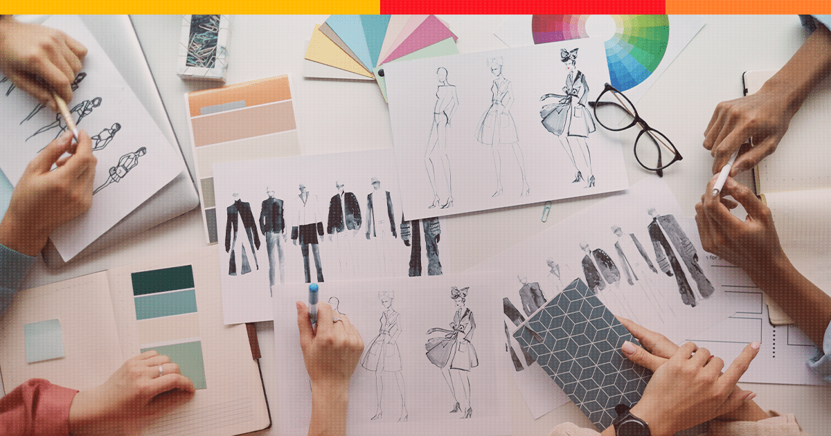 Mesa com vários papéis com desenhos e ferramentas de cores para desenvolver artigos de moda. Remete ao tema do artigo: Fashion Law.